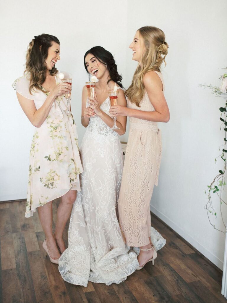 Bride-to-be celebrating with friends at a garden-inspired bridal shower, each holding champagne glasses and smiling in the Vella Nest Floral studio.